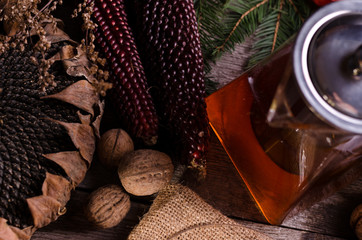 Autumn cozy still life with Glass teapot and cup of tea on a gunny napkin, sunflower, brown maizes and physalises. Good For Social Media Posts.