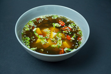 Miso soup with tofu and herbs. Asian food. Dark background. Space for text.