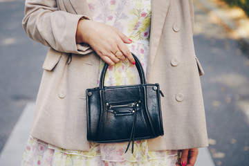 street style detail of a fashionable woman wearing an oversized blazer, vintage floral dress and a black trendy mini bag handbag. perfect 2019 trend fall fashion outfit details.