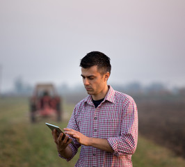 Farmer with tablet in front of tractor