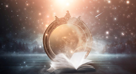 An open book and a magic mirror against the backdrop of a night landscape. Abstract dark scene,...