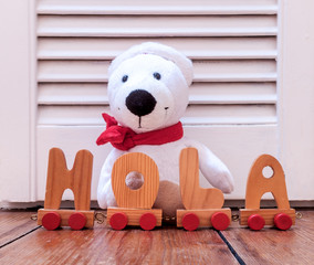 cuddly brown furry toy with wooden letters making the Spanish word hola. Concept for children © Erik_AJV