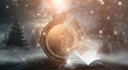 An open book and a magic mirror against the backdrop of a night landscape. Abstract dark scene,...