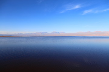 Blue lake with calm waters,  in the horizon mountains and blue clean sky. Atacama desert, Chile.
