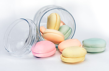 Round colored marshmallows in a transparent glass jar. Sweet dessert - multi-colored macaroons on a white background.