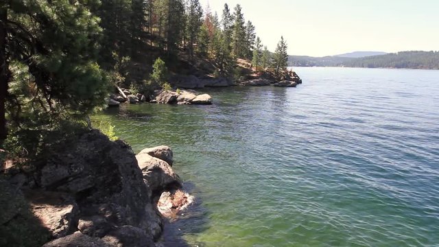 Late summer in lake Coeur d' Alene in Northern Idaho, with clear inviting waters and The famous hiking trail of Tubs Hill in the background
