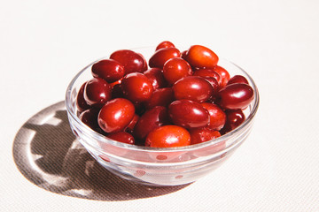 Red cornel berries in glass bowl on pink background