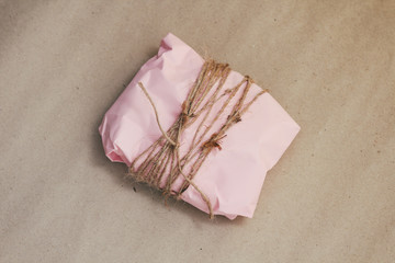 Soft pouch wrapped in craft paper and tie cord. Crumpled paper background texture. Delivery service. Online shopping.