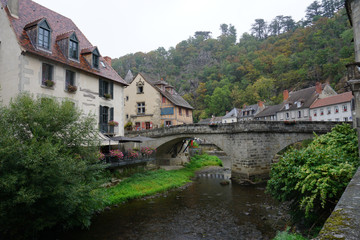 Fototapeta na wymiar old stone bridge over the river and village in France