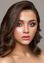 A very beautiful young girl with colorful trendy smoky eyes, bright blue eyes and natural wavy hairdo. - obrazy, fototapety, plakaty