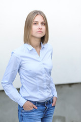 Fototapeta premium Blonde bussiness woman dressed casual with a perfect smile, standing near a white wall