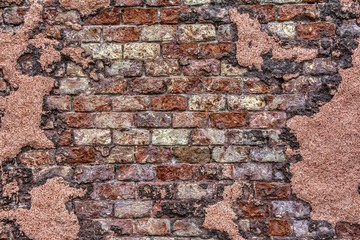 Old brick wall with peeling plaster.