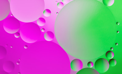 Colorful abstract background. Pink, green circles and oil bubbles in the water closeup. Macro abstraction.