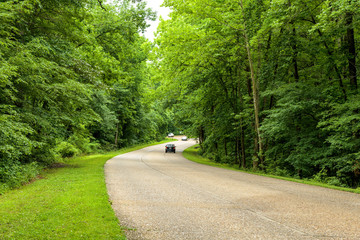 Colonial Parkway - A few cars cruising on broad three-lane Colonial Parkway, winding through a...