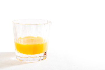 A glass tumbler filled with orange juice isolated on a white background