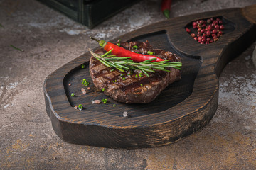 Close view of fillet mignon on wooden board, dark photo