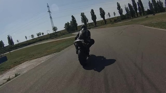 A black motorcyclist on a bike on a racetrack turns in a circle to the right