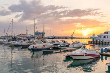 Fototapeta premium Yellow sunset in the sea harbor with moored yachts.