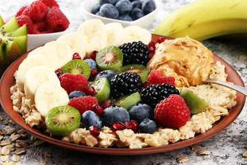 Bowl of oatmeal porridge with banana, raspberries coconut and caramel sauce on rustic table, hot and healthy food for Breakfast