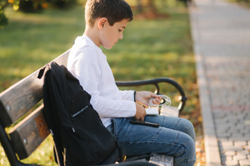 Fototapeta na wymiar Teenage boy in white shirt use powerbank for charging his smartphone otside. Low battery on smartphone