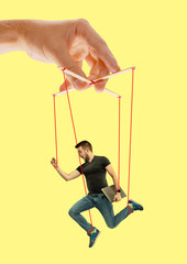 Man like a puppet in somebodies hands on yellow background. Concept of unfair manipulation,...