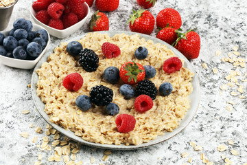 Bowl of oatmeal porridge with banana, raspberries coconut and caramel sauce on rustic table, hot and healthy food for Breakfast