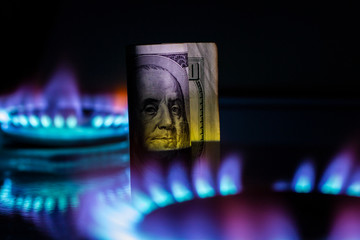 a hundred dollar bill on a gas burner with a burning fire on a black background, the front and back...