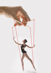 Woman like a puppet in somebodies hands on grey background. Concept of unfair manipulation,...