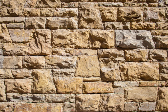 Wall of embossed stone bricks, masonry stone texture
