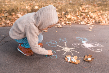 little boy of 4-5 years old, autumn day summer city park, draws with crayons, have fun playing. Warm casual wear sweater with hood. Caring love and parenting weekend, nature. Free space.