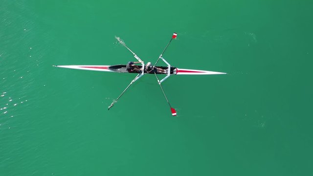 Aerial drone bird's eye view video of sport canoe operated by team of young women in deep blue sea waters