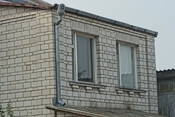 Fototapeta na wymiar two large windows on the gray brick wall of the house