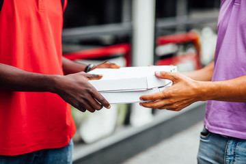Close up photo of happy man from delivery service in red t-shirt and guy giving food order and holding two pizza boxes.