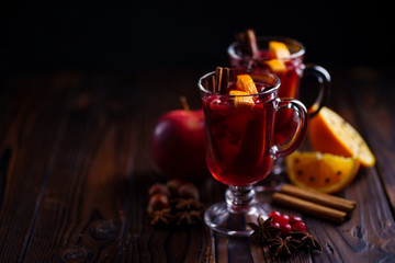 Mulled wine with aromatic spices and fruits on wooden rustic table, copy space. Traditional Christmas time hot drink