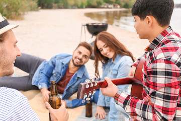 Friends drinking beer at barbecue party near river