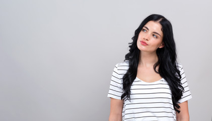 Young woman in a thoughtful pose on a gray background