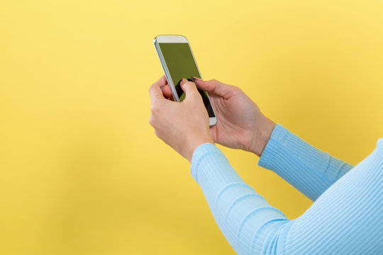 Woman using her smartphone on a yellow background