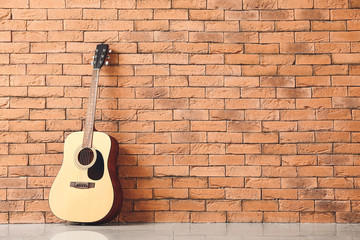Modern acoustic guitar near brick wall