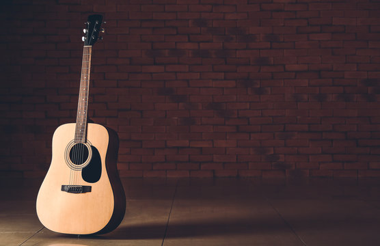 Modern acoustic guitar against dark wall © Pixel-Shot