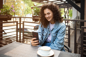 Young pretty woman in cafe using mobile phone.