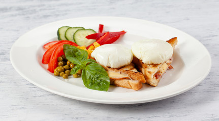 Ñrispy toast with ham and cheese, poached eggs, fresh vegetables and sauce.