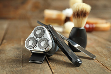 Obraz premium Electric shaver with razor and brush on wooden table