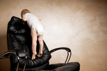 child playing climbed onto the back of a large office chair