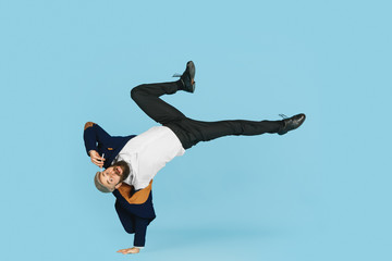 Young caucasian businessman having fun dancing break dance on blue studio background. Management, flexible, freedom, professional occupation, alternative way of modern working. Loves his job