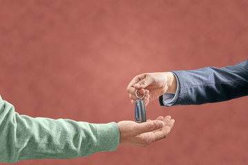 hand with suit delivers car keys to another hand with pullover. car delivery concept