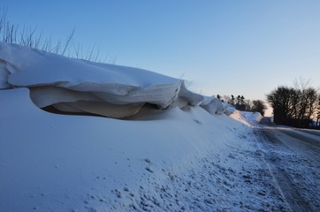 Snowdrifts near road on a cold afternoon