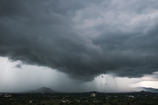 Heavy down pour/cloud burst over the distant hill/mountains in Pune, Maharashtra, India. Dark, stormy scenery background for meteorology/weather background. 
