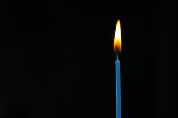 single candle with flame on a black background