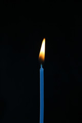 single candle with flame on a black background
