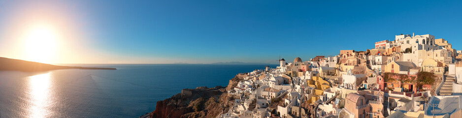 Sunset over Santorini island in Greece. Traditional church, apartments and windmills in Oia village.